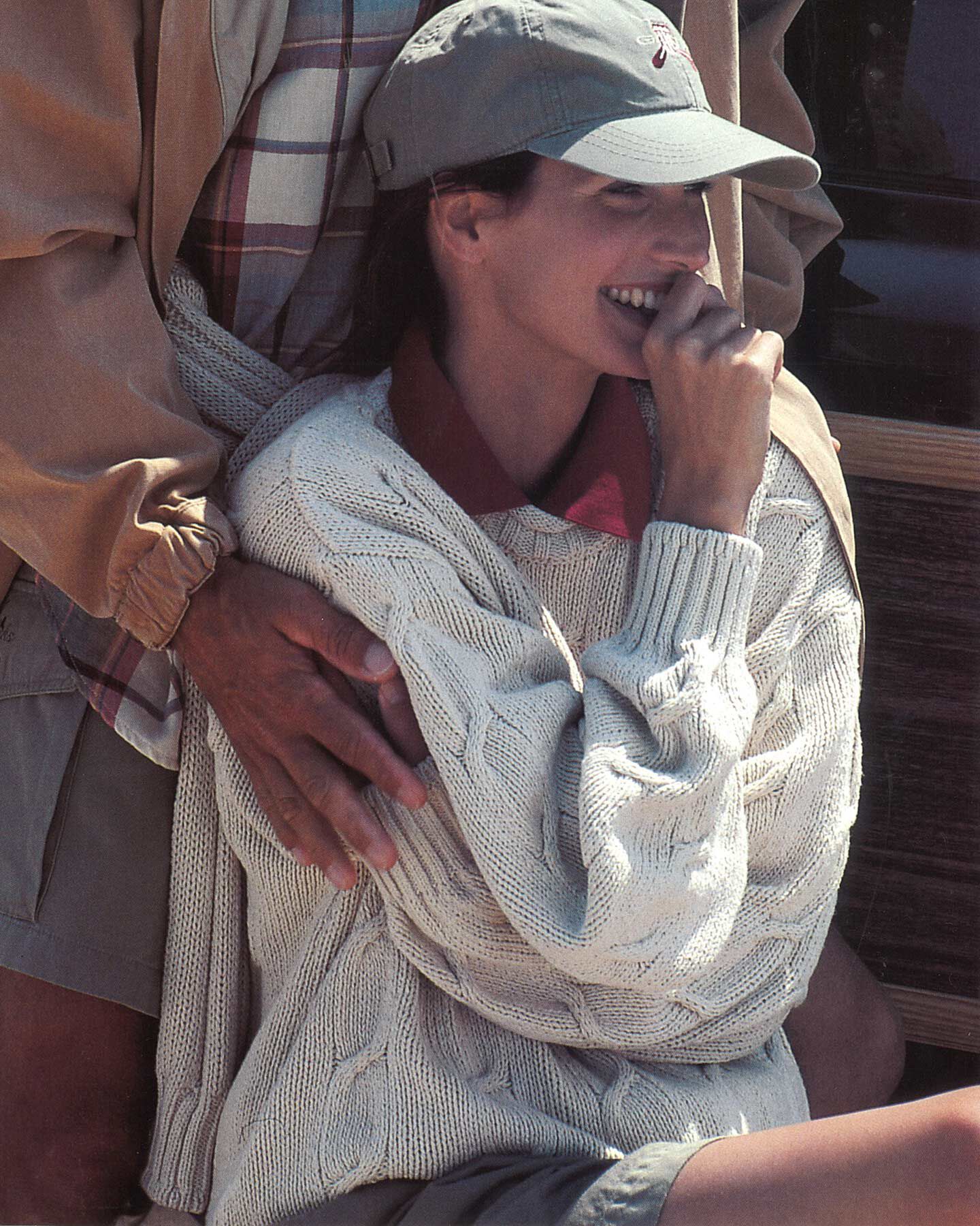 Woman in a cable-knit Gant sweater and a cap.