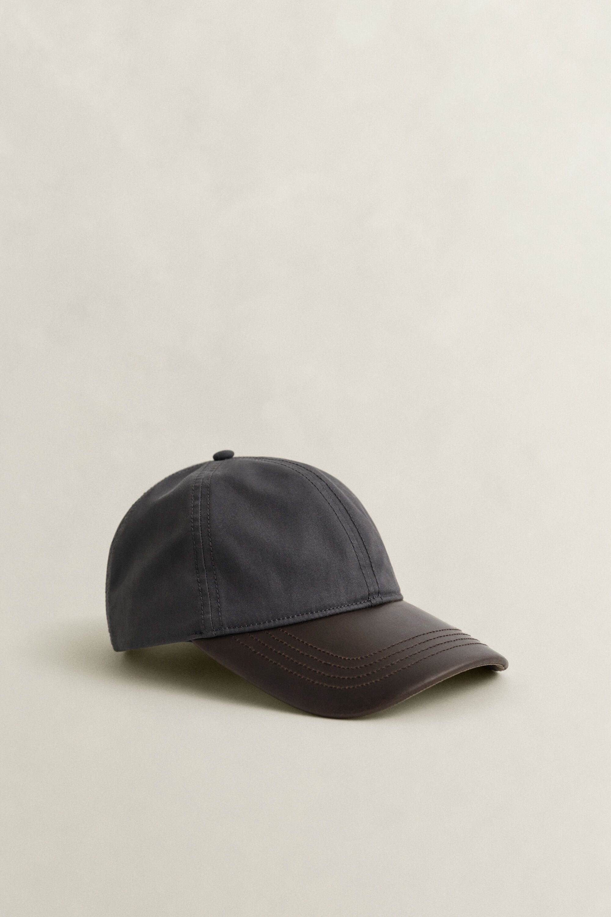 Cappellino con visiera in pelle cerata